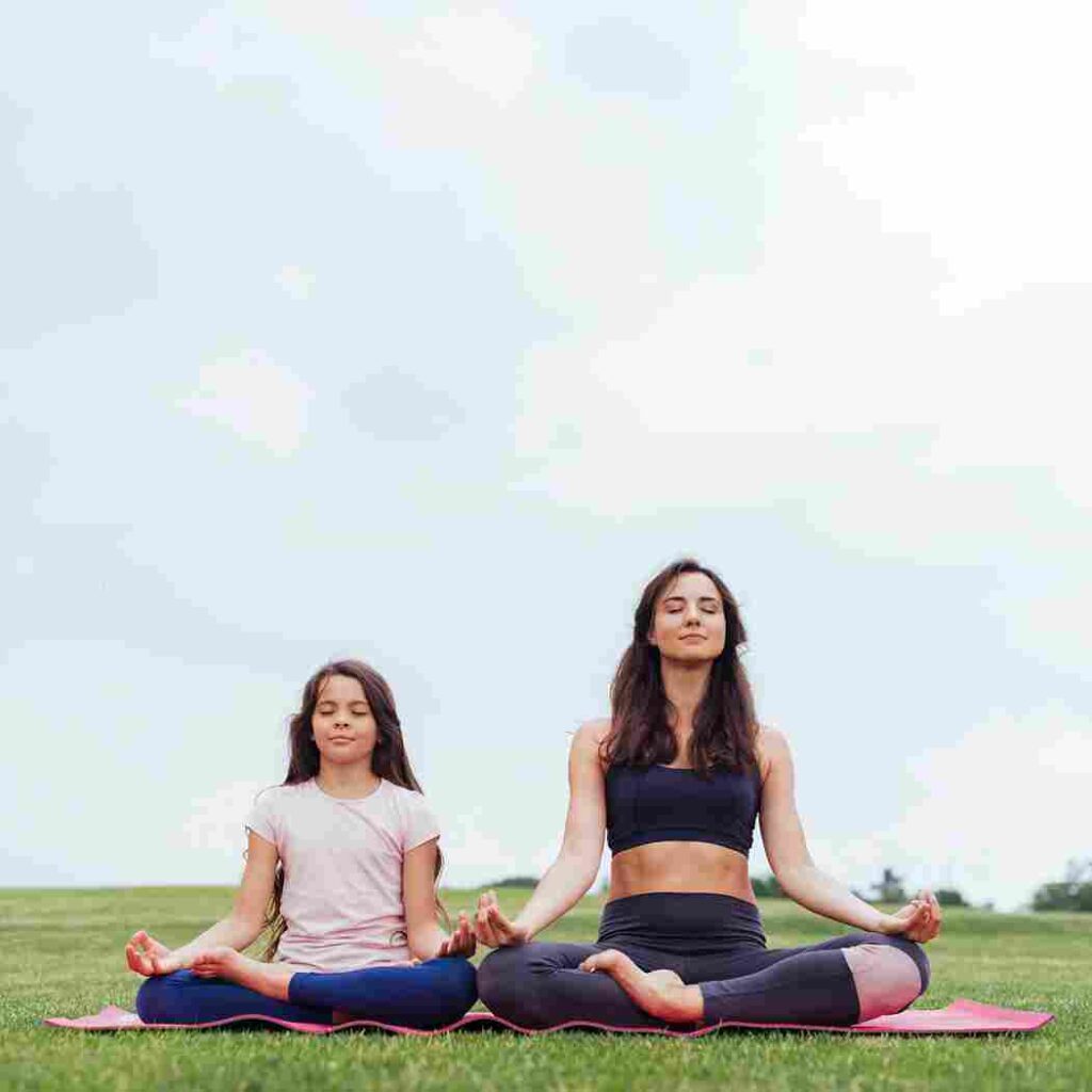 front view mother daughter meditating outdoors 11zon