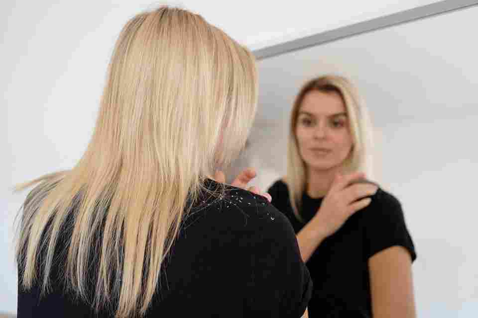 medium shot woman with dandruff looking mirror 11zon