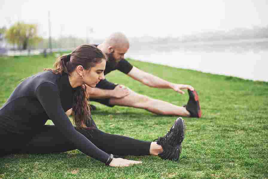 fitness couple stretching outdoors park near water young bearded man woman exercising together morning 11zon