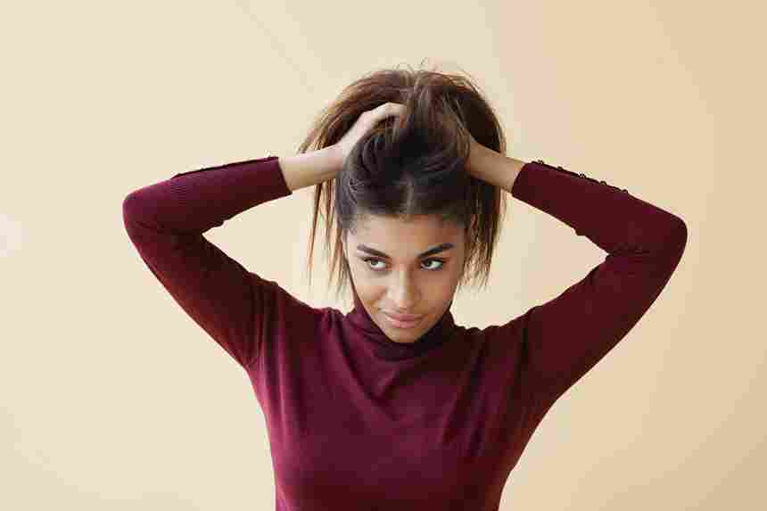 portrait elegant young afro american woman trendy turtleneck sweater looking away with mysterious smile as if having some great idea while doing her hair getting ready work morning 11zon